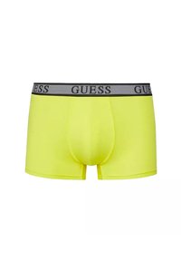 Boxer-briefs jaunes avec une ceinture élastique grise portant le logo "GUESS" répété tout autour. Tissu lisse, design ajusté, et longueur mi-cuisse.