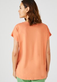 Korte mouwen, losse t-shirt in koraaloranje, gemaakt van een zachte stof, met een ronde halslijn en een rechte zoom.
