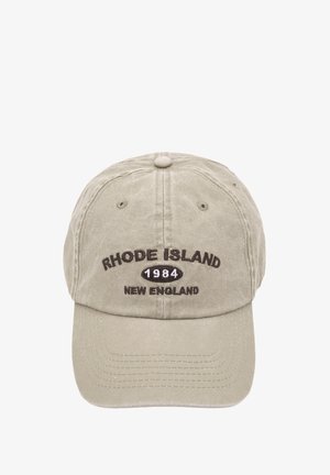 Bomuldsbaseballcap i lys beige med broderet tekst: "Rhode Island 1984 New England" i mørkebrun på frontpanelet.