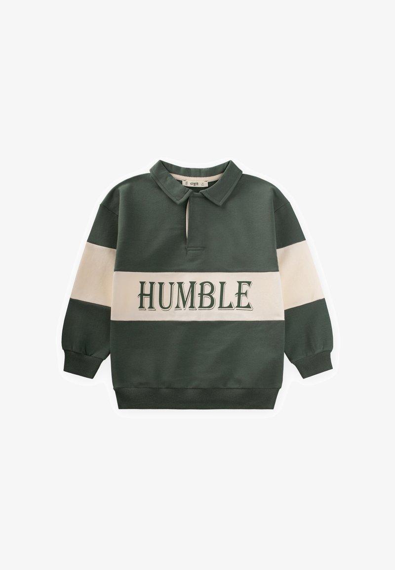 Tumed roheline poolking ja kollane. Omab kreemjaid horisontaalseid triibe ja sõna "HUMBLE" rohelise värviga, minu ees embleemitud.