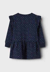 Vestido azul marino con mangas largas, patrones de corazones blancos y rosas, hombros con volantes, cinturilla elástica y falda acampanada.