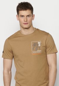 T-shirt à manches courtes de couleur beige, en coton, arborant un graphique de tigre et le texte "JAPON TOKYO" en orange et gris sur le devant.