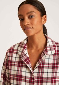 Camicia a quadri rossa e bianca con colletto e texture morbida. Presenta linee nere in contrasto nel motivo e una vestibilità comoda.