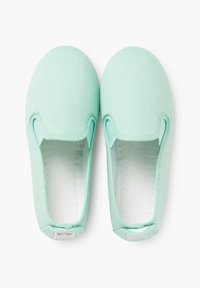Licht mintgroene instappers vervaardigd uit canvas met een gladde textuur en elastische zijpanelen, voorzien van een witte voering en een label.