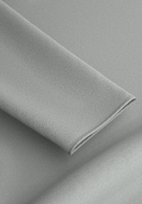 Hellgrauer strukturierter Stoff, der über sich selbst gefaltet ist, mit glatter Oberfläche und feinem Gewebe-Muster. Die Kanten sind sauber gesäumt.