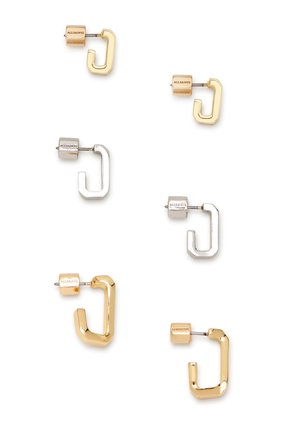 Due paia di orecchini geometrici in oro e argento. Ciascuno presenta un perno a blocco con il nome del marchio. Le forme sono rotonde e angolari.