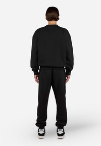 Sort sweatshirt og matchende joggers, sweatshirt med rund halsudskæring og ribbede manchetter, joggers med tapered ben og elastisk talje.
