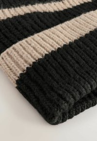 Coperta lavorata a maglia con strisce alternate di nero e beige chiaro, caratterizzata da una superficie texturizzata e un design a coste spesse per un maggiore calore.