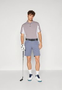 Helehall valgega kaunistatud polosärk, kombineeritud helesiniste lühikeste pükstega. Komplekti kuuluvad golfikindad ja valged kingad siniste detailidega.