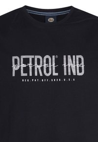 Zwarte katoenen t-shirt met witte opdruk "PETROL IND" en een geschreven "petrol" ontwerp. Ronde hals, korte mouwen, casual pasvorm.