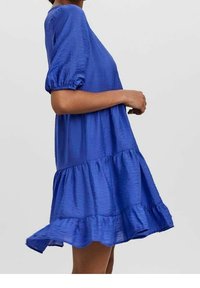 Modrá šaty s krátkým rukávem, s nabíranými rukávy a vrstveným, volánkovým lemem. Vyrobeno z lehké, mírně zmačkané tkaniny.