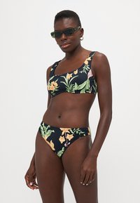 Bikini floreale nero, con vivaci stampe tropicali arancioni e verdi. Il top ha un collo a quadrato; il fondo è a vita bassa con arricciature laterali.