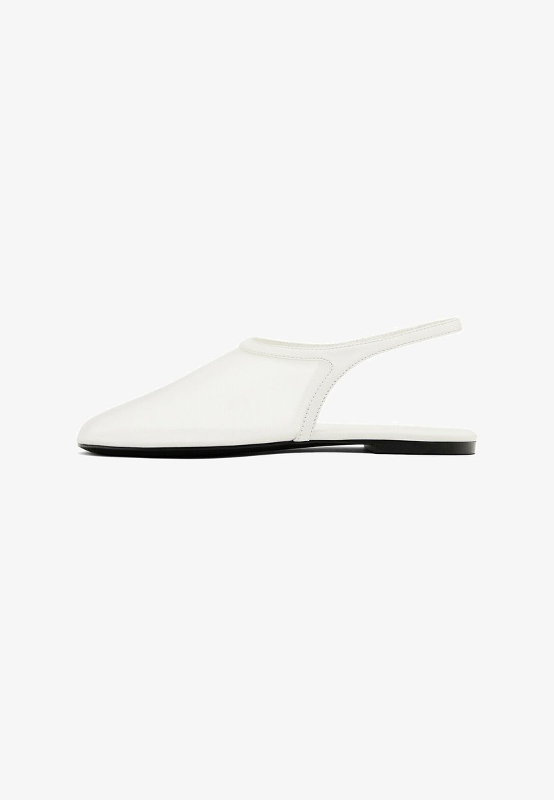 Chaussure plate blanche à bride arrière, bout pointu fermé et fine semelle noire sur fond blanc.