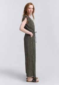 Gestreepte jumpsuit met korte fladdermouwen, een cinched taille en zijzakken. Het kleurenpalet bevat zwarte en crème strepen.