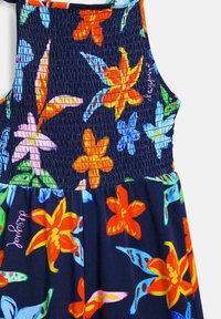 Bloemendess in een navy kleur met een smock-bodice, versierd met levendige rode, oranje en blauwe bloemen en groene bladeren.