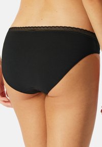 Culotte en coton noir avec un bord en dentelle le long de la taille, texture lisse et design couvrant entièrement à l'arrière.