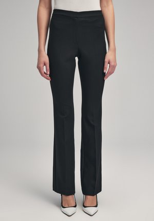 Zwarte op maat gemaakte broek met een gladde textuur, recht gesneden ontwerp en geen zichtbare zakken, gecombineerd met puntige witte hakken.