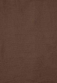 Brauner Stoff mit einer strukturierten, gewellten Oberfläche. Das Material wirkt weich und leicht, geeignet für verschiedene textile Anwendungen.