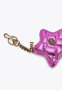 Różowa metaliczna sakiewka w kształcie gwiazdy z pikowanym wzorem, z zapięciem w kolorze złotym i ozdobnym emblematem z przodu.