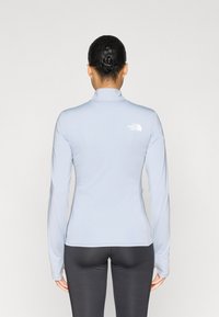 Ανοιχτό μπλε μακρυμάνικη μπλούζα με ψηλό γιακά, που διαθέτει ένα μικρό λευκό λογότυπο στο πίσω μέρος. Λείο ύφασμα και εφαρμοστή γραμμή.