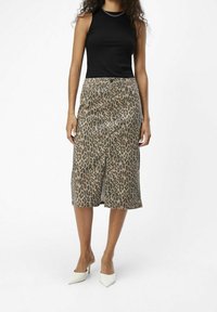 Jupe midi à imprimé léopard avec une fente avant, confectionnée en tissu léger ; associée à un haut noir sans manches et des talons blancs pointus.