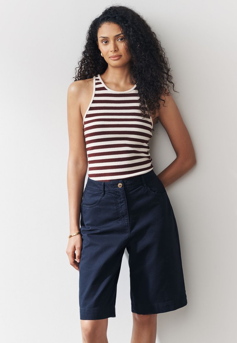 Débardeur rayé marron et crème, assorti à un short bleu marine jusqu'aux genoux avec poches avant et fermeture à boutons.