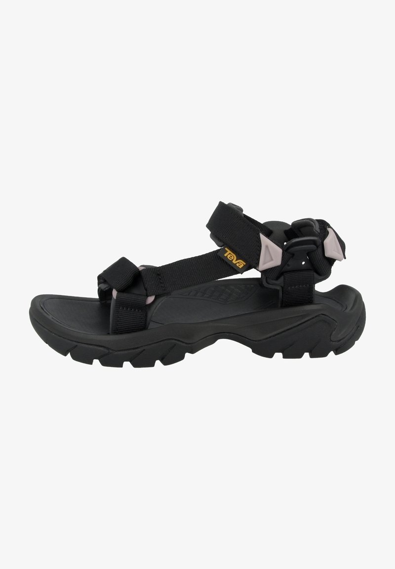 Sandale noire d'extérieur avec des sangles ajustables, une semelle épaisse et robuste, et un petit logo jaune Teva sur la bride latérale.