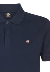 Mörkblå pikétröja i texturerad bomull, med en treknappslå och en liten röd och vit broderad logotyp på bröstet.