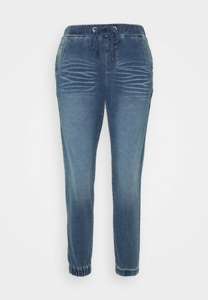 Pantalon jogger en denim bleu avec taille et poignets élastiques, cordon de serrage, poches latérales et effet délavé horizontal en forme de moustaches sur l'avant des cuisses.