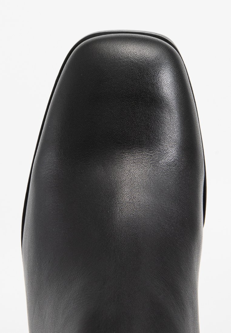 Stivale alla caviglia in pelle nera con superficie lucida, punta quadrata e texture liscia. Design minimalista senza hardware o accenti visibili.