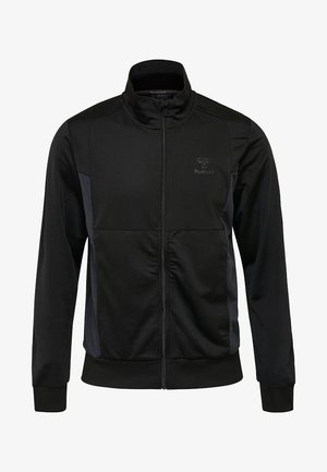 Veste de sport noire à fermeture éclair intégrale avec col montant, poignets et ourlet côtelés, et logo discret sur le côté gauche de la poitrine.