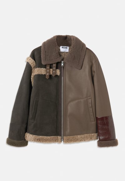 Pruun ja tumeoliivne lambanaha jakk, millel on lukuavamine, suur krae, kaks taskut ja vastandlikud nahkadetailid varrukatel ja kehal.