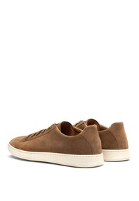 Braune Wildledersneaker mit niedrigem Profil, abgerundetem Zeh und cremefarbener Gummisohle. Sie verfügen über flache Schnürsenkel und minimale Nähdetails.