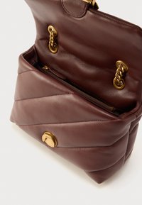 Χειροποίητη δερμάτινη τσάντα σε βουργουνδί απόχρωση με κεντητό σχέδιο, χρυσές μεταλλικές λεπτομέρειες και εσωτερική τσέπη με φερμουάρ. Διαθέτει μαγνητικό κλείσιμο και διακοσμητικές αλυσίδες.