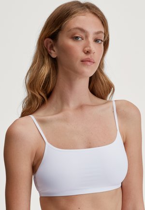 Witte naadloze bralette met dunne verstelbare bandjes, rechthoekige halslijn, gladde textuur en een aangesloten pasvorm. Eenvoudige en minimalistische stijl.