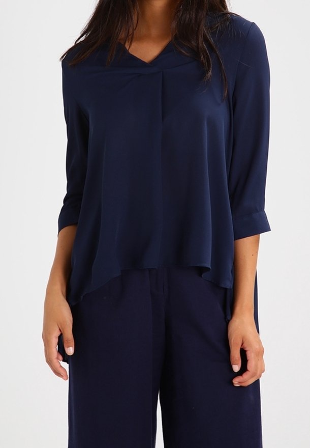 Blusa leggera blu navy con scollo a V, maniche a tre quarti e design fluido. Texture liscia con dettagli morbidi drappeggiati.