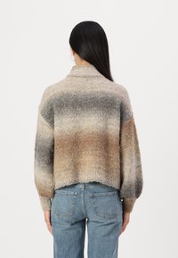 Maglione morbido e oversize con colletto alto, caratterizzato da una sfumatura di toni beige, grigi e marroni. Polsini a costine e orlo rilassato.