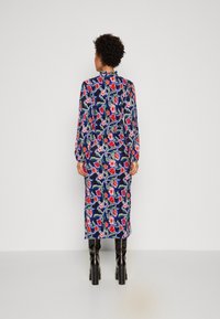 Vestido midi floral con base azul marino y patrones en rojo y rosa, de manga larga y corte recto, combinado con botas negras hasta la rodilla.
