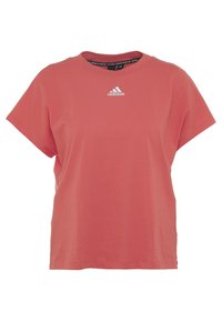 Camiseta de algodón rosa claro con cuello redondo, mangas cortas y un logotipo de Adidas bordado en blanco en el pecho. Corte casual, textura suave.