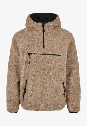 Harmaa fleece-poolo korkealla kauluksella, vetoketjullisella eturemmillä ja kahdella sivuvetoketjullisella taskulla. Ominaisuuksiin kuuluvat mustat vetoketjuakselit ja teksturoitu pinta.