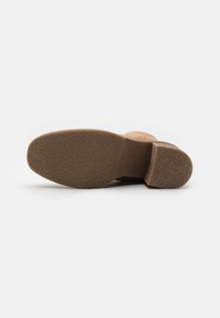 Suela de goma marrón con agarre texturizado, tacón ligeramente elevado y superficie superior suave. Diseñada para estabilidad y durabilidad.