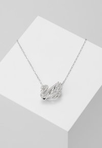 Silver necklace featuring a swan pendant decorated with small clear crystals, on a delicate chain, displayed on a white box.
