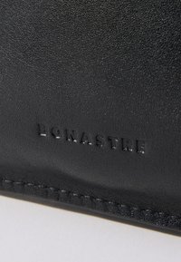 Svart lærplånbok med en teksturert overflate, preget logo "BONASTRE," og kontrasterende sømdetaljer langs kanten.