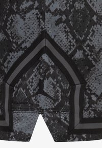 Czarny i szary materiał w wzór węża z siateczkowymi detalami. Posiada kanciasty dół, kontrastowe czarne akcenty oraz logo Jumpman na środku.