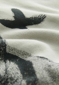 Țesătură din bumbac cu o suprafață texturată, având un design abstract de pasăre neagră pe un fundal gri deschis. Un contrast subtil evidențiază detaliile.