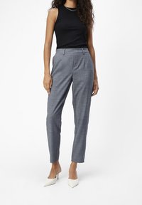 Pantaloni grigi a quadri con vestibilità sartoriale, caratterizzati da un girovita medio, pieghe frontali e tasche a filetto, abbinati a un top senza maniche nero.