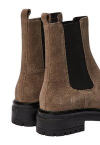 Bottes Chelsea en daim marron avec des panneaux latéraux élastiques noirs, bout rond et semelles en caoutchouc noir épais ; surface texturée et languettes de tirage.