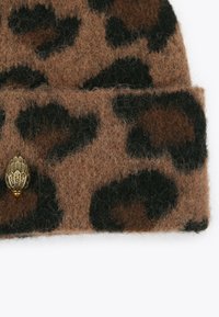 Brązowy czapka z wełny w nadruk panterki z podwiniętym brzegiem. Posiada złoty dekoracyjny akcent z metalu oraz miękką, teksturowaną tkaninę.