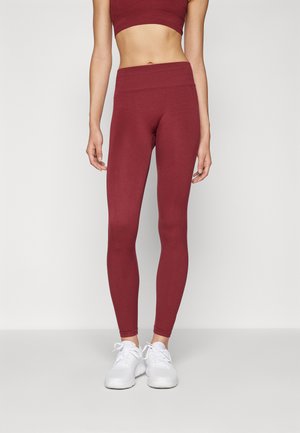 Leggings bordeaux aderenti con una vita alta, realizzati in materiale elasticizzato. Abbinati a scarpe da ginnastica bianche per un look sportivo.