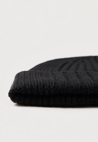 Berretto nero lavorato a maglia con una texture a coste e un bordo pieghevole, realizzato in un materiale morbido simile alla lana per calore e comfort.